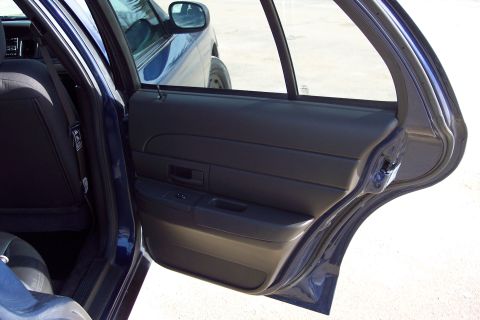 2001 Ford Crown Victoria - Interior view of a 2001 Ford Crown Victoria, showing the dark door panel and rear seating area.
