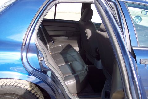 2001 Ford Crown Victoria - Interior view of a blue sedan's back seat and open doors.