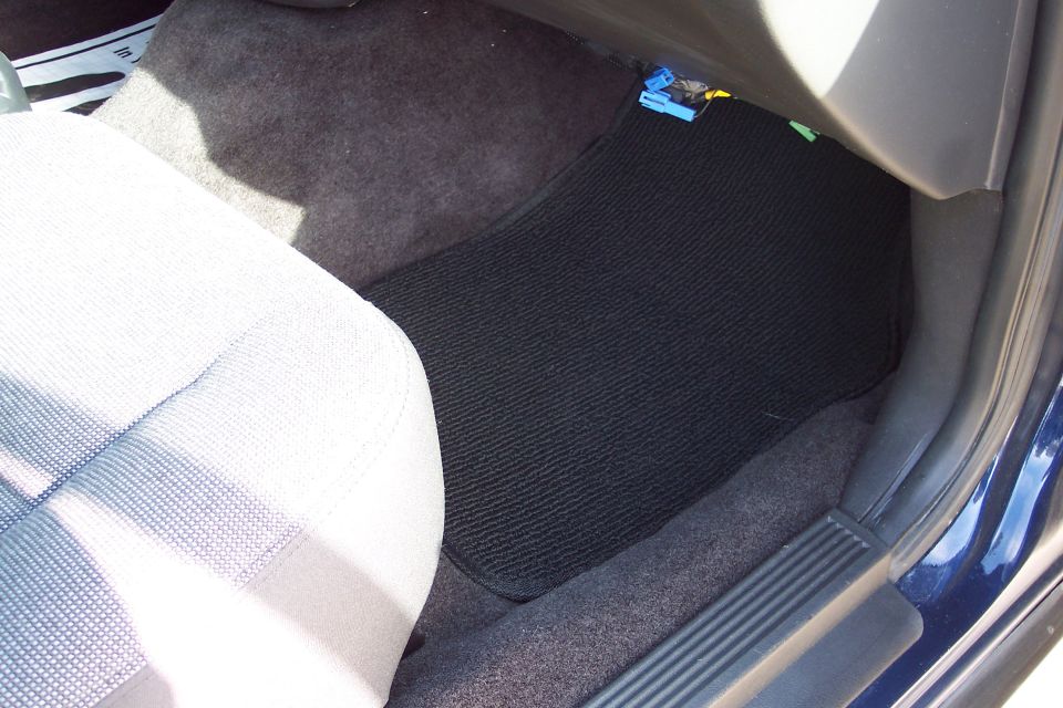 Car interior showing driver's side floor mat and part of the seat