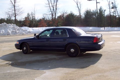 2001 Ford Crown Victoria - Side view of a dark blue 2001 Ford Crown Victoria sedan parked outdoors on a bright, cold day.