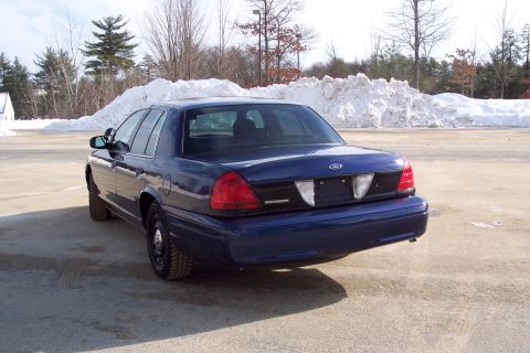 2001 Ford Crown Victoria - Rear view of a blue sedan parked outdoors with snowbanks behind it.