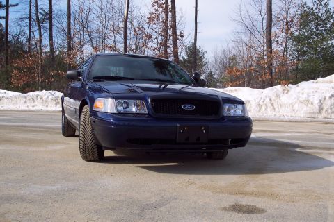 2001 Ford Crown Victoria - A dark blue 2001 Ford Crown Victoria is parked outdoors in front of a wooded area with snow on the ground.