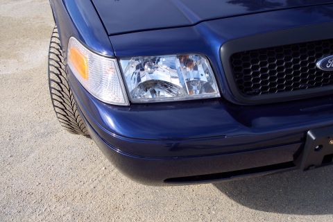 2001 Ford Crown Victoria - Front corner of a blue 2001 Ford Crown Victoria, close-up on the headlight and grille.