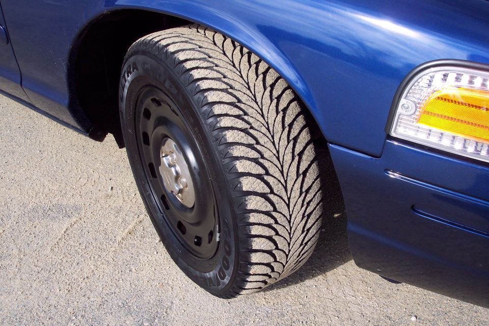 Blue 2001 Ford Crown Victoria front fender and wheel with sand-covered tire