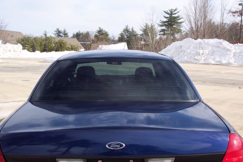 2001 Ford Crown Victoria - Rear view of a dark blue sedan, likely a 2001 Ford Crown Victoria, with snow in the background.