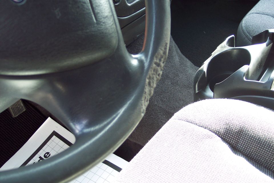 Steering wheel with worn grip and a paper with grid lines and text 'side' visible