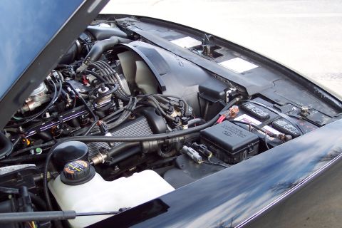 2001 Ford Crown Victoria - The engine bay of a black car is shown with the hood open, revealing the engine and related components.