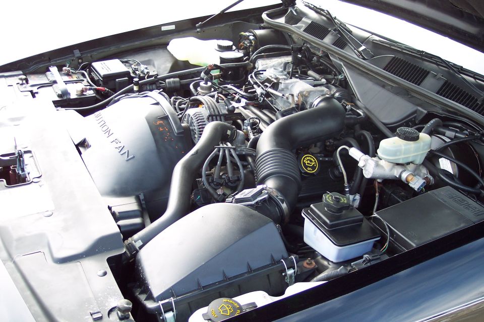 Engine bay of a 2001 Ford Crown Victoria. Shows the air intake, battery, and brake fluid reservoir