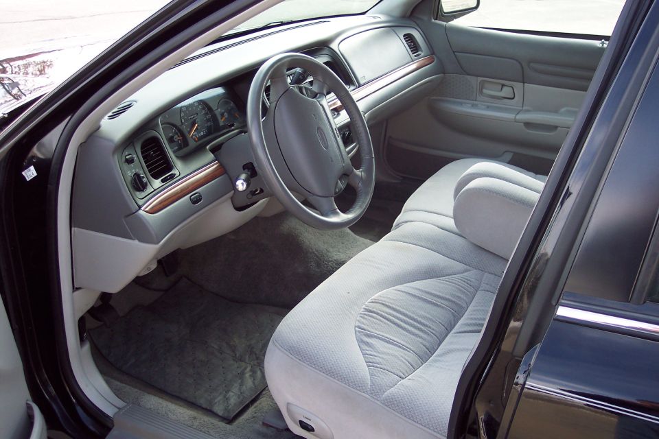 2001 Ford Crown Victoria interior, light grey cloth seats, dashboard with wood trim, viewed from passenger side door
