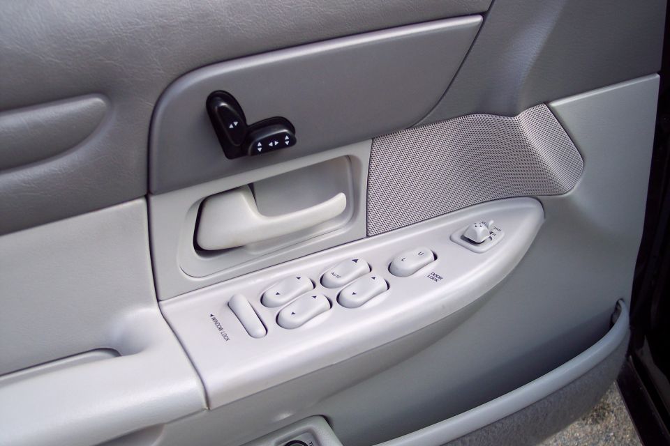Driver's side door panel with power window and seat controls. Shows window lock, four window buttons, and mirror adjustment