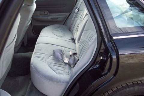 2001 Ford Crown Victoria - Interior view of the rear seating area of a black car, showing gray cloth upholstery and seatbelts.