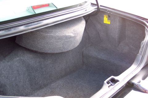 2001 Ford Crown Victoria - The interior of a car's trunk, showing the spare tire compartment and a yellow sticker on the side panel.