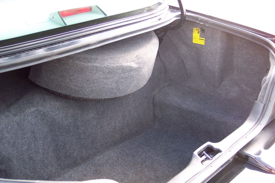 Car trunk interior with spare tire well and yellow warning sticker
