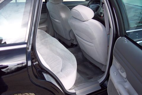 2001 Ford Crown Victoria - The interior of a car, showing the back seat and part of the front seats with light gray cloth upholstery.