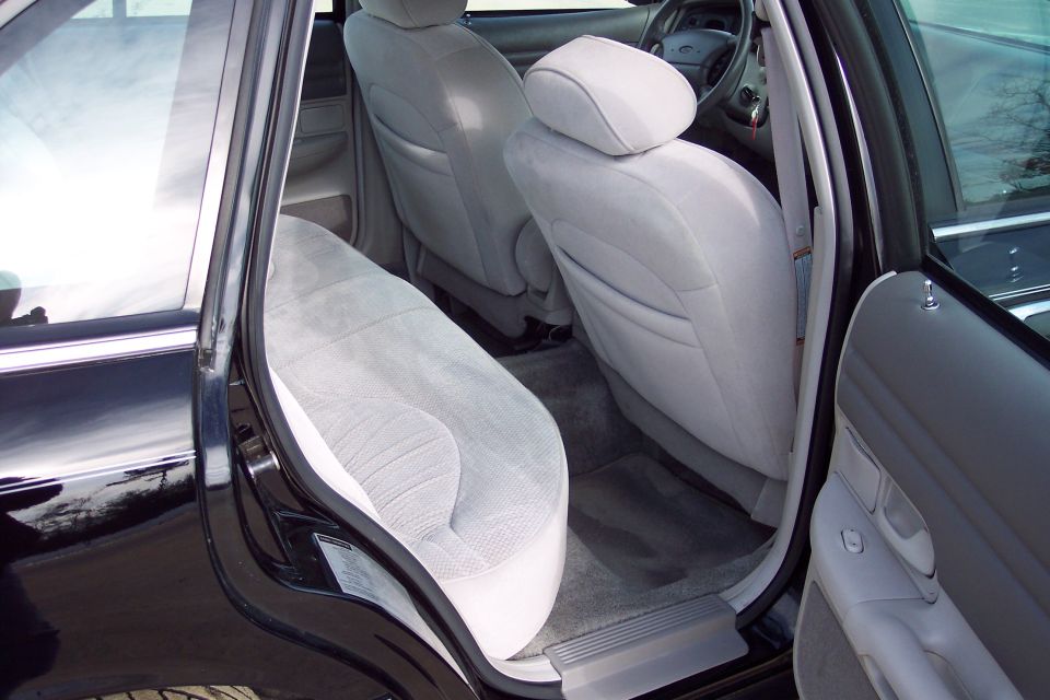 Interior view of a black car's back seat and front seats. Shows light gray cloth upholstery