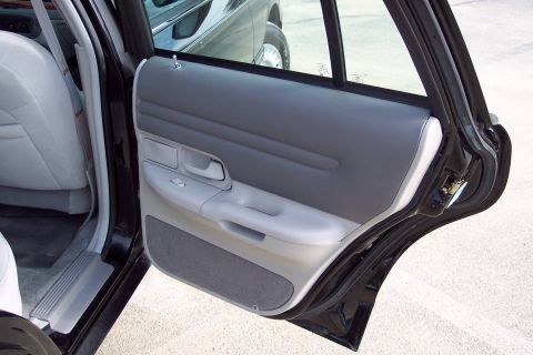 2001 Ford Crown Victoria - Interior view of a dark sedan, showing the gray door panel and rear seat.
