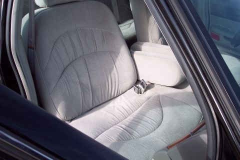 2001 Ford Crown Victoria - Interior view of a car's front seats and armrest, showing the fabric texture and a seatbelt buckle.