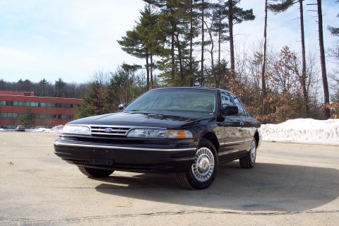 2001 Ford Crown Victoria - A black 2001 Ford Crown Victoria is parked outdoors on a sunny day with snow in the background.