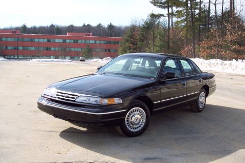 2001 Ford Crown Victoria - Black Ford Crown Victoria sedan parked outdoors in front of a brick building and trees.