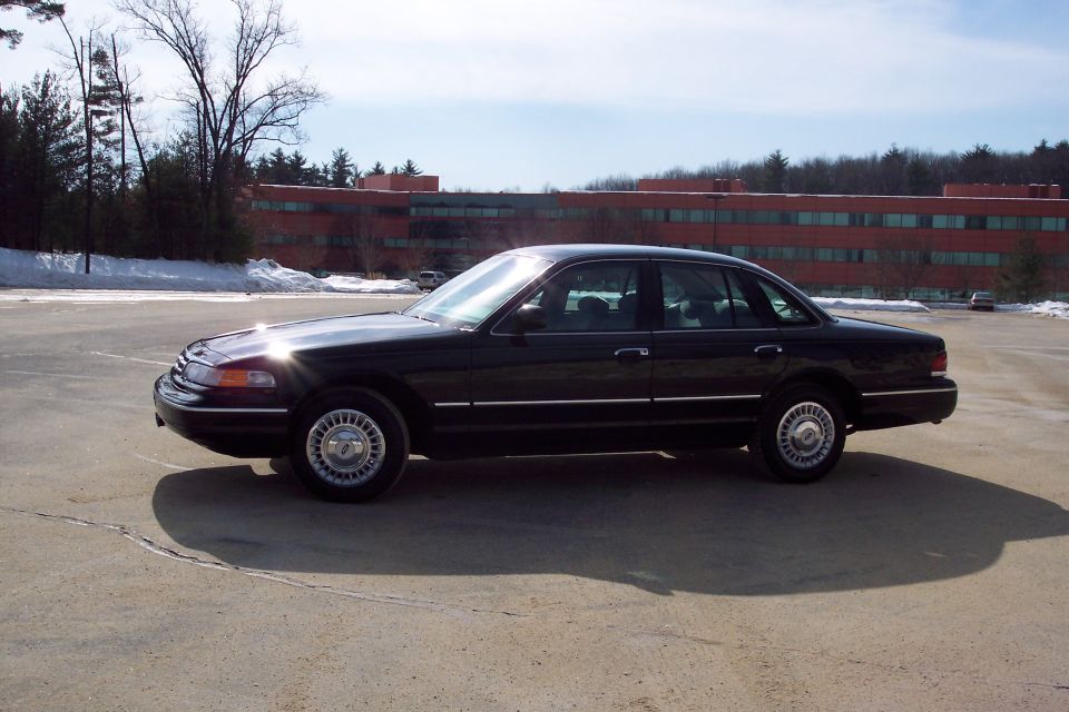 Black 2001 Ford Crown Victoria sedan parked on asphalt, side view