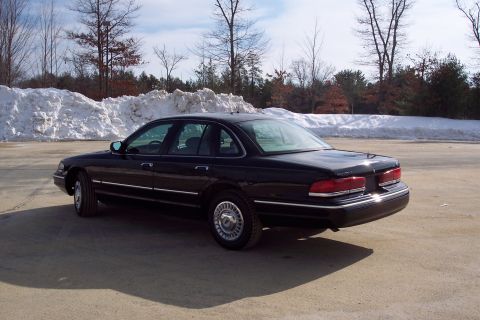 2001 Ford Crown Victoria - A black sedan is parked outdoors with snowbanks and trees visible behind it.