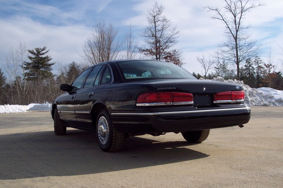 Black 2001 Ford Crown Victoria rear quarter view, showing chrome trim and snowbanks in background