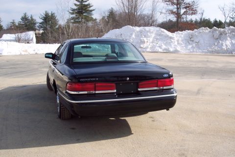 2001 Ford Crown Victoria - Rear view of a black 2001 Ford Crown Victoria parked in a lot with snow in the background.