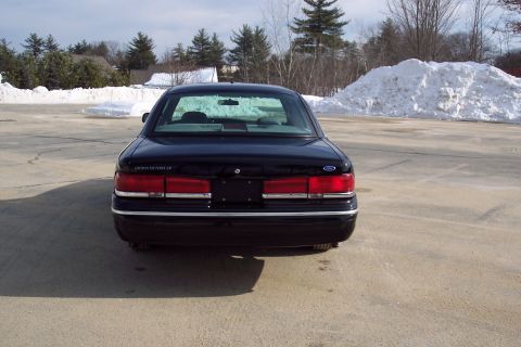 2001 Ford Crown Victoria - A black 2001 Ford Crown Victoria is parked in a lot with snowbanks visible.