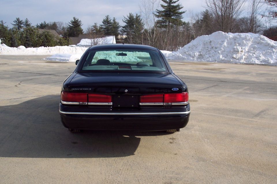 Rear view of a black 2001 Ford Crown Victoria parked outside with snow piles in the background