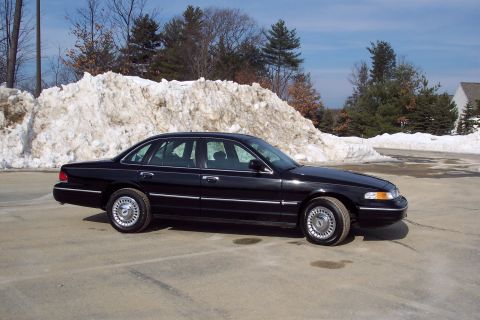 2001 Ford Crown Victoria - A black 2001 Ford Crown Victoria is seen from the front three-quarter angle with a snowbank in the background.