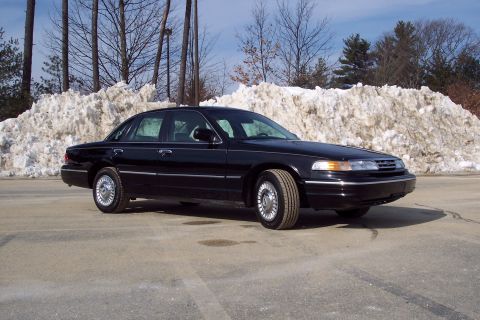2001 Ford Crown Victoria - A black 2001 Ford Crown Victoria is shown from a three-quarter front view, parked in front of a large pile of snow.