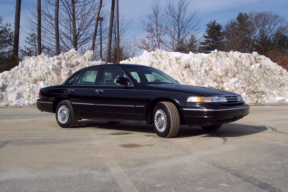 Black 2001 Ford Crown Victoria parked outside with snow piles in background