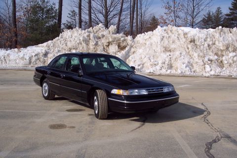 2001 Ford Crown Victoria - A black Ford Crown Victoria sedan is parked outdoors with snowdrifts behind it.