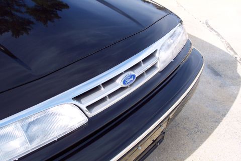 2001 Ford Crown Victoria - Close-up of a black Ford Crown Victoria's front grille and headlight assembly.