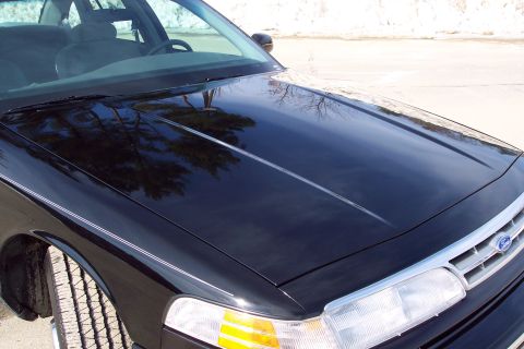 2001 Ford Crown Victoria - The front of a black 2001 Ford Crown Victoria is shown, with reflections on the hood.