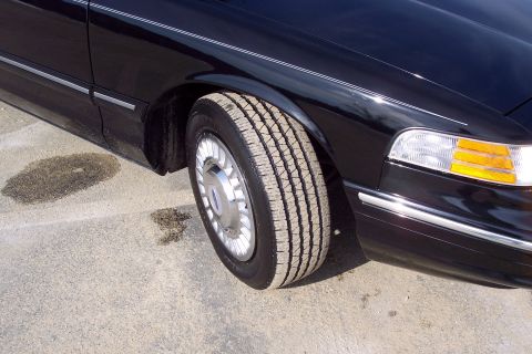 2001 Ford Crown Victoria - Close-up of a black 2001 Ford Crown Victoria's front wheel well and fender.