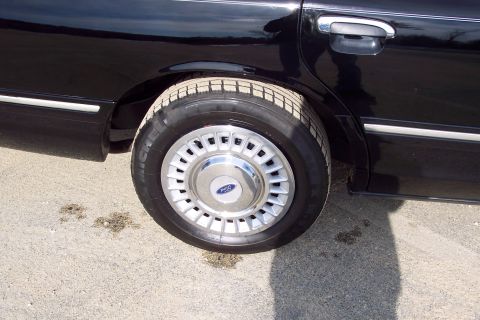 2001 Ford Crown Victoria - Close-up of the rear wheel and side of a black 2001 Ford Crown Victoria.