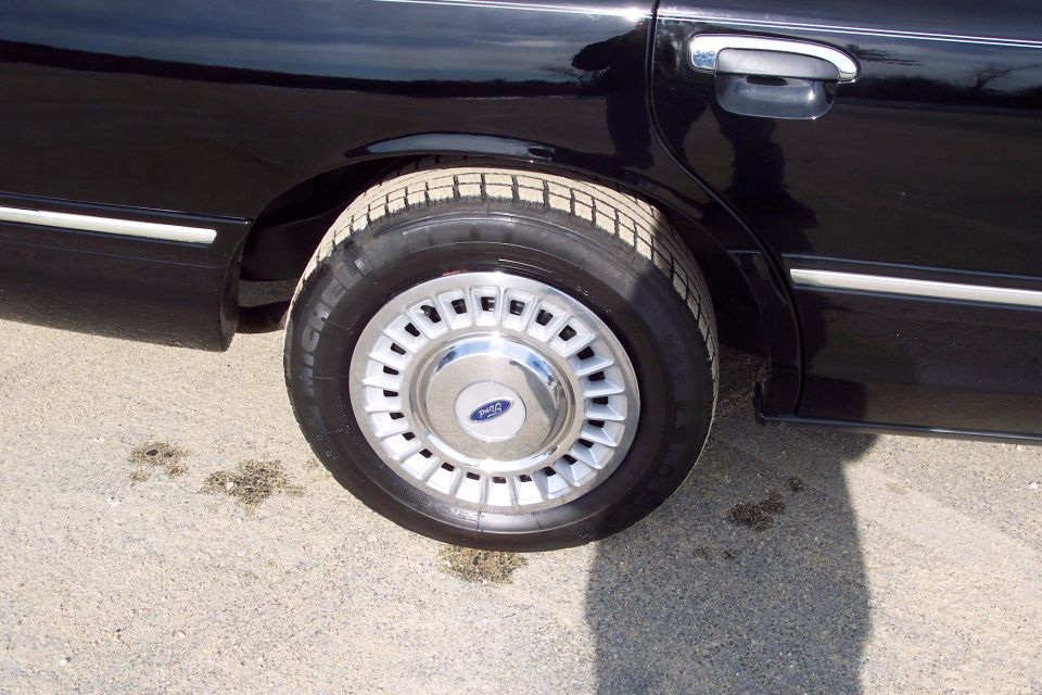 Rear wheel and lower door panel of a black 2001 Ford Crown Victoria