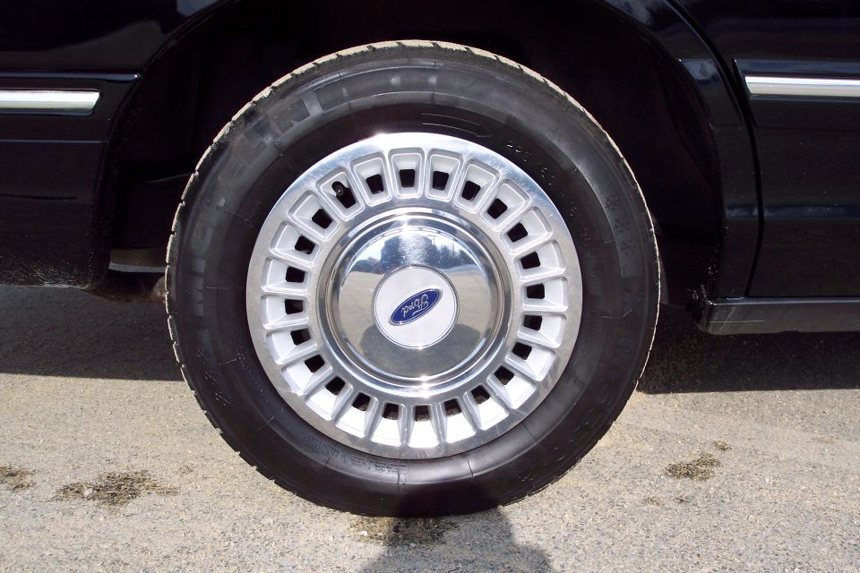 Close-up of a 2001 Ford Crown Victoria's front wheel and tire. The hubcap has a Ford logo