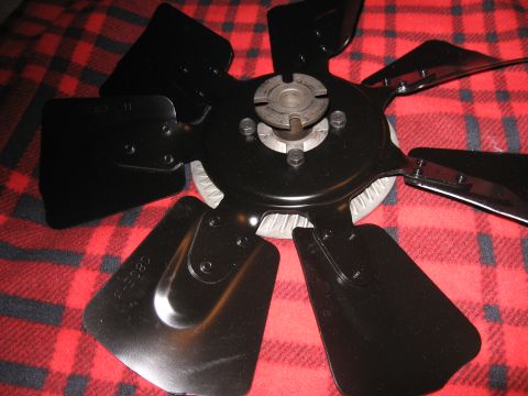 1968 Shelby GT500 - A black engine fan part, likely for a classic car, is shown against a red plaid background.