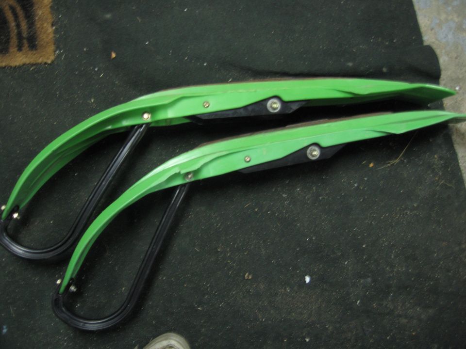 Pair of green snowmobile skis with black metal runners