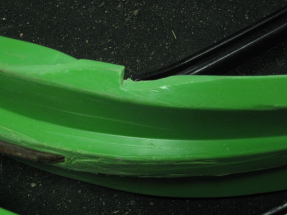 Close-up of a green plastic snowmobile part with some damage