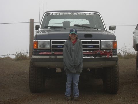 1991 Ford Bronco - A young person stands in front of a dark blue Ford Bronco with "2 BIG BRONCOS 4X4 CLUB" text on the windshield. The vehicle has large off-r…