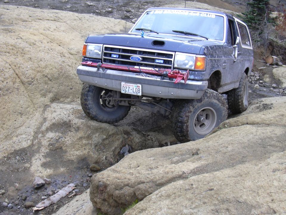 1991 Ford Bronco off-roading on a rocky trail, front tire elevated.