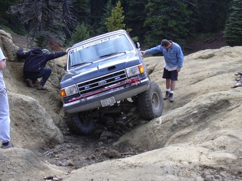 1991 Ford Bronco - A Ford Bronco navigates a challenging off-road course with assistance from onlookers.