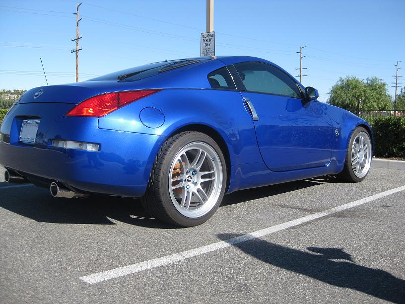 Metallic blue Nissan 350Z coupe from the rear three-quarter on silver aftermarket wheels