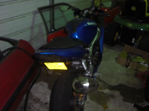 1988 Ford Bronco - A blue motorcycle is parked in a garage, with a red car and lawnmower visible in the background.