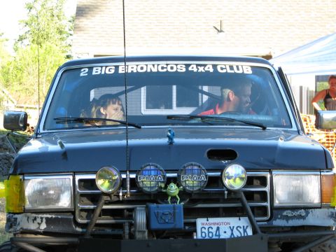 1991 Ford Bronco - Front view of a black Ford Bronco with custom off-road modifications and a club sticker on the windshield.