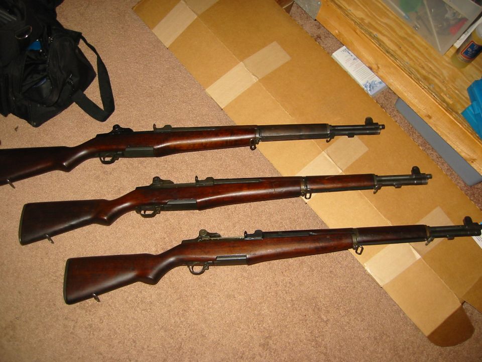 Three M1 Garand rifles laid out on a carpeted floor