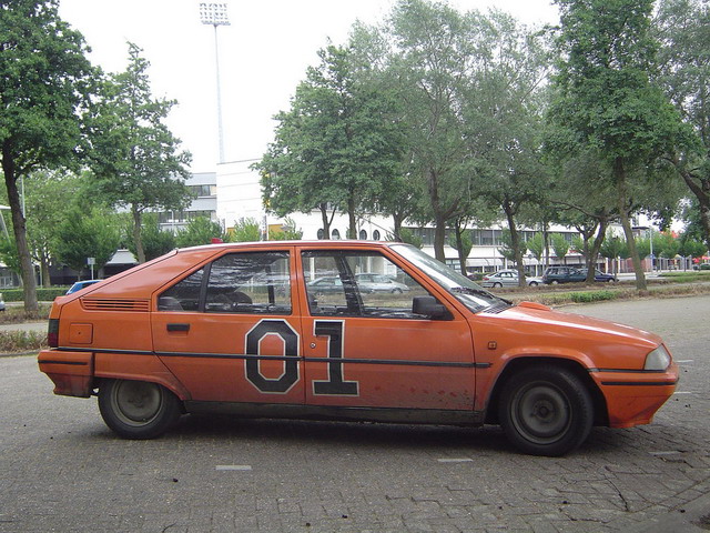 Orange hatchback with black number 01 on the door, parked on asphalt